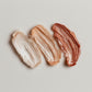 Three swatches of different beige and brown makeup shades on a light background