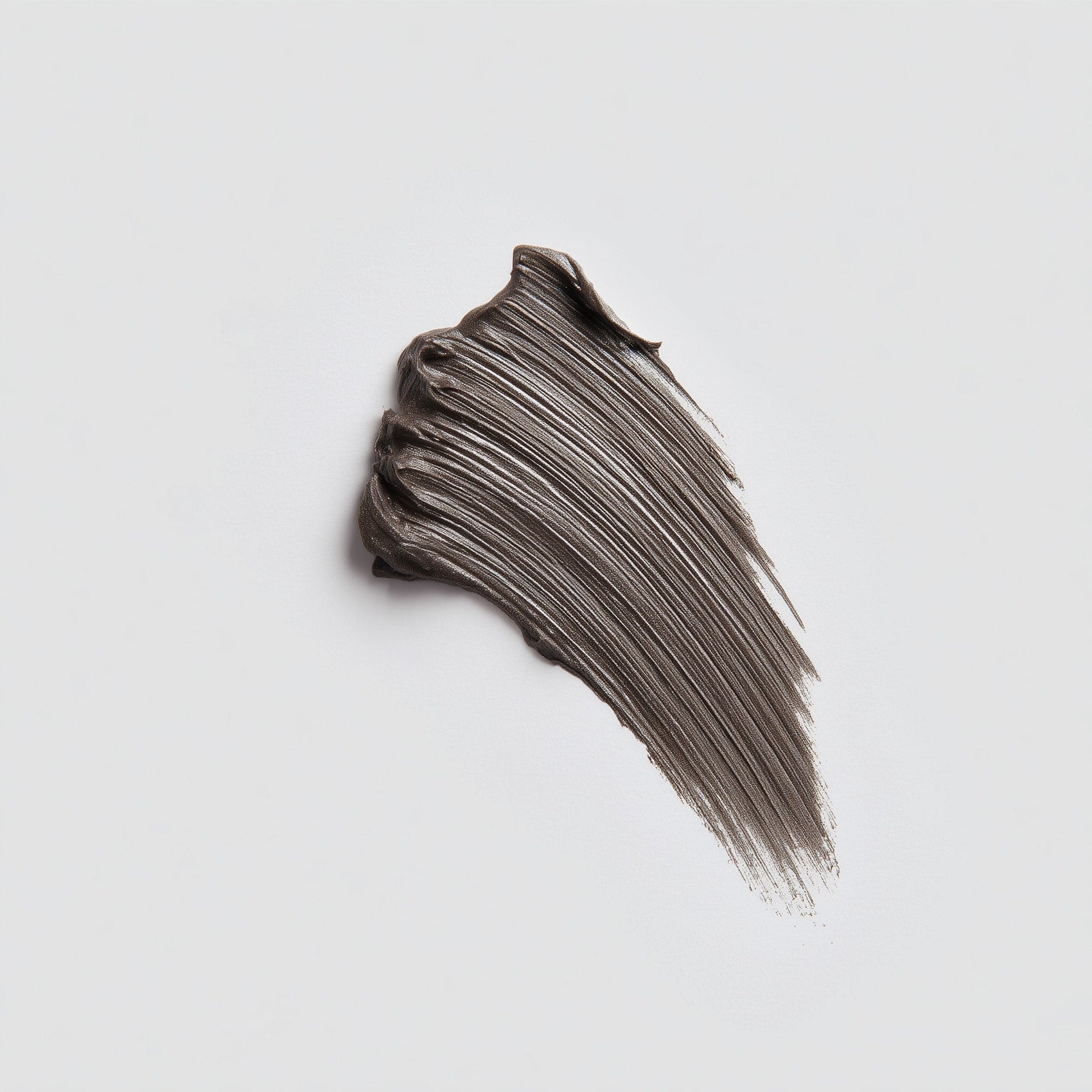 Swatch of dark brown makeup cream on a light gray background (Brown)