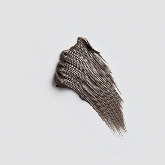 Swatch of dark brown makeup cream on a light gray background (Brown)