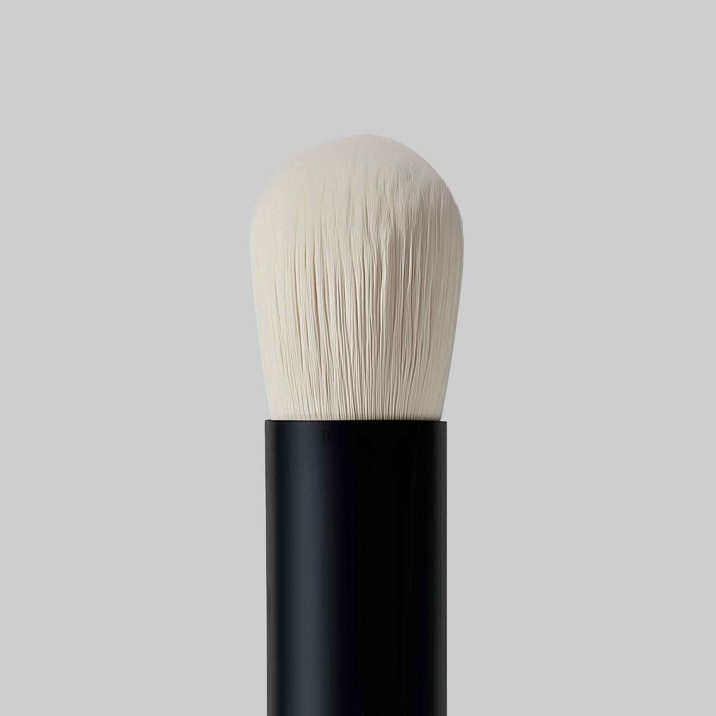 Makeup brush with black handle and white bristles on a gray background