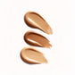 Three swatches of beige makeup cream on a white background