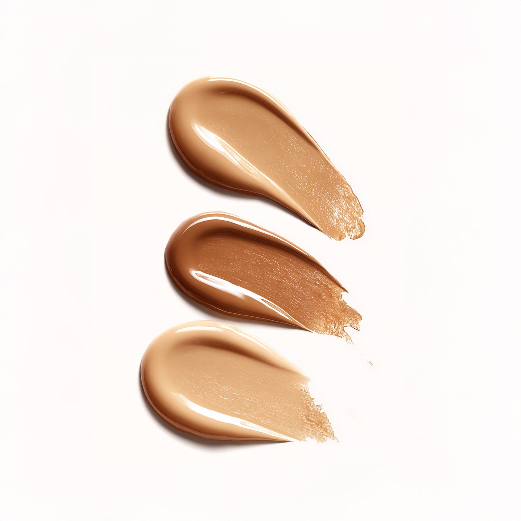 Three swatches of beige makeup cream on a white background
