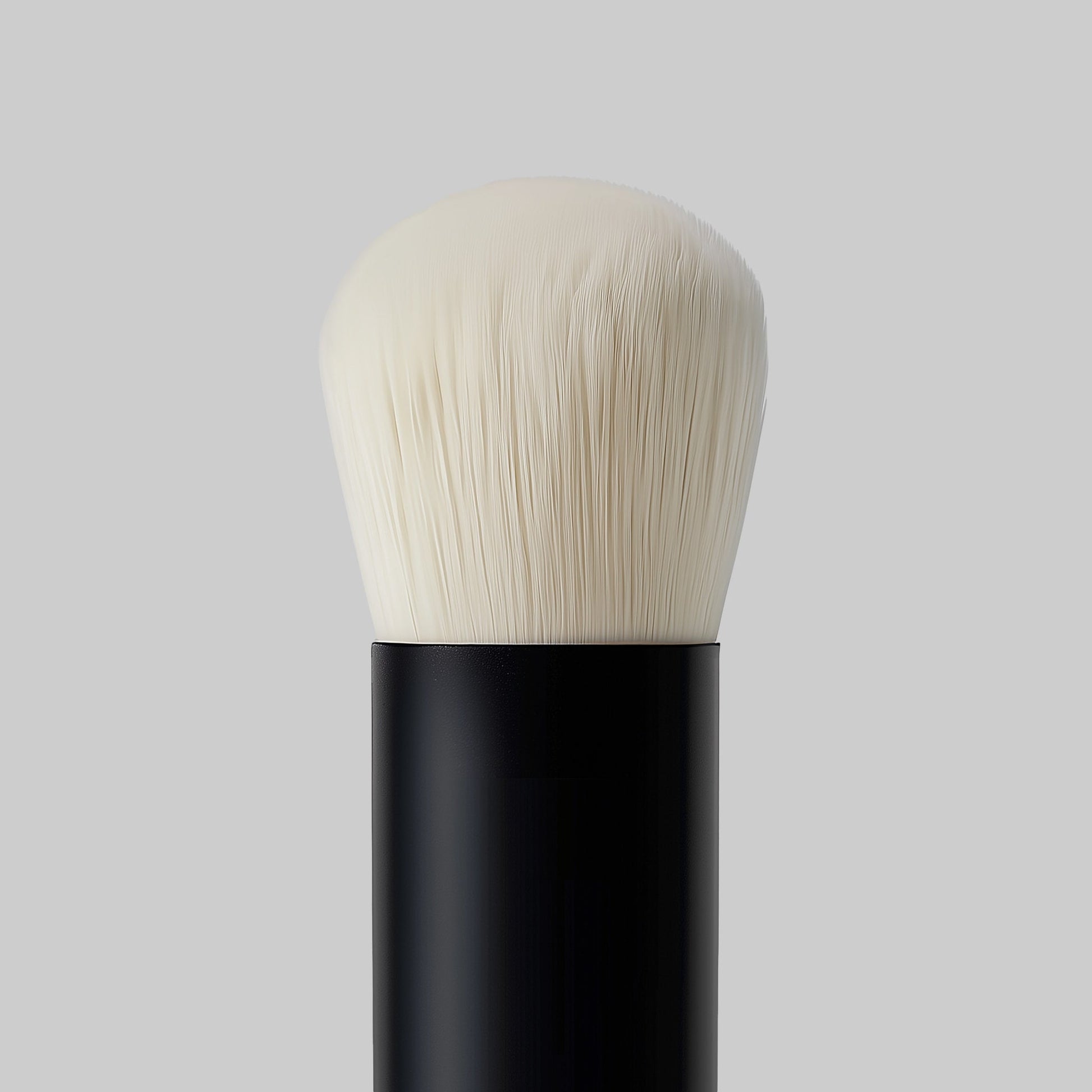 Makeup brush with black handle and white bristles on a gray background