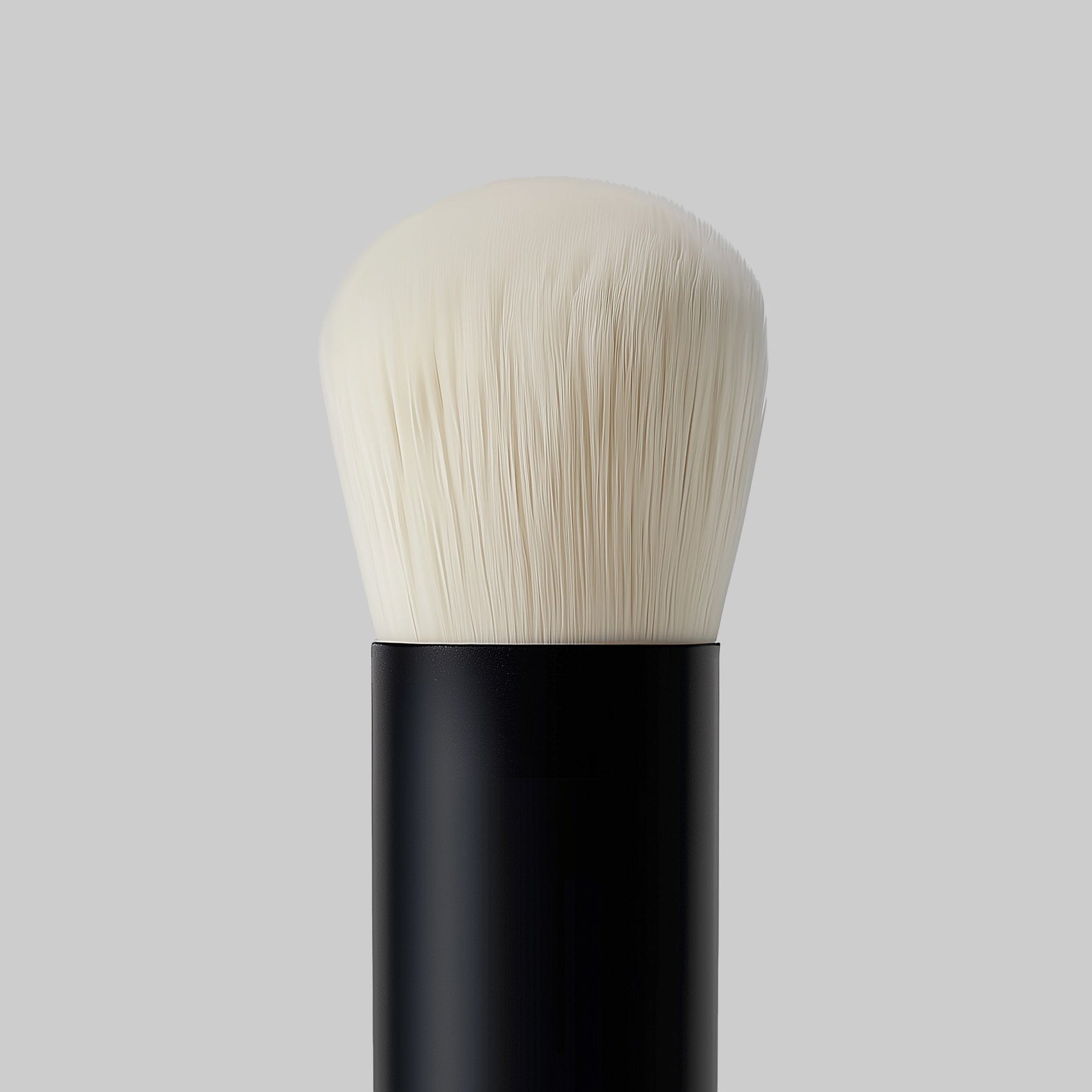 Makeup brush with black handle and white bristles on a gray background
