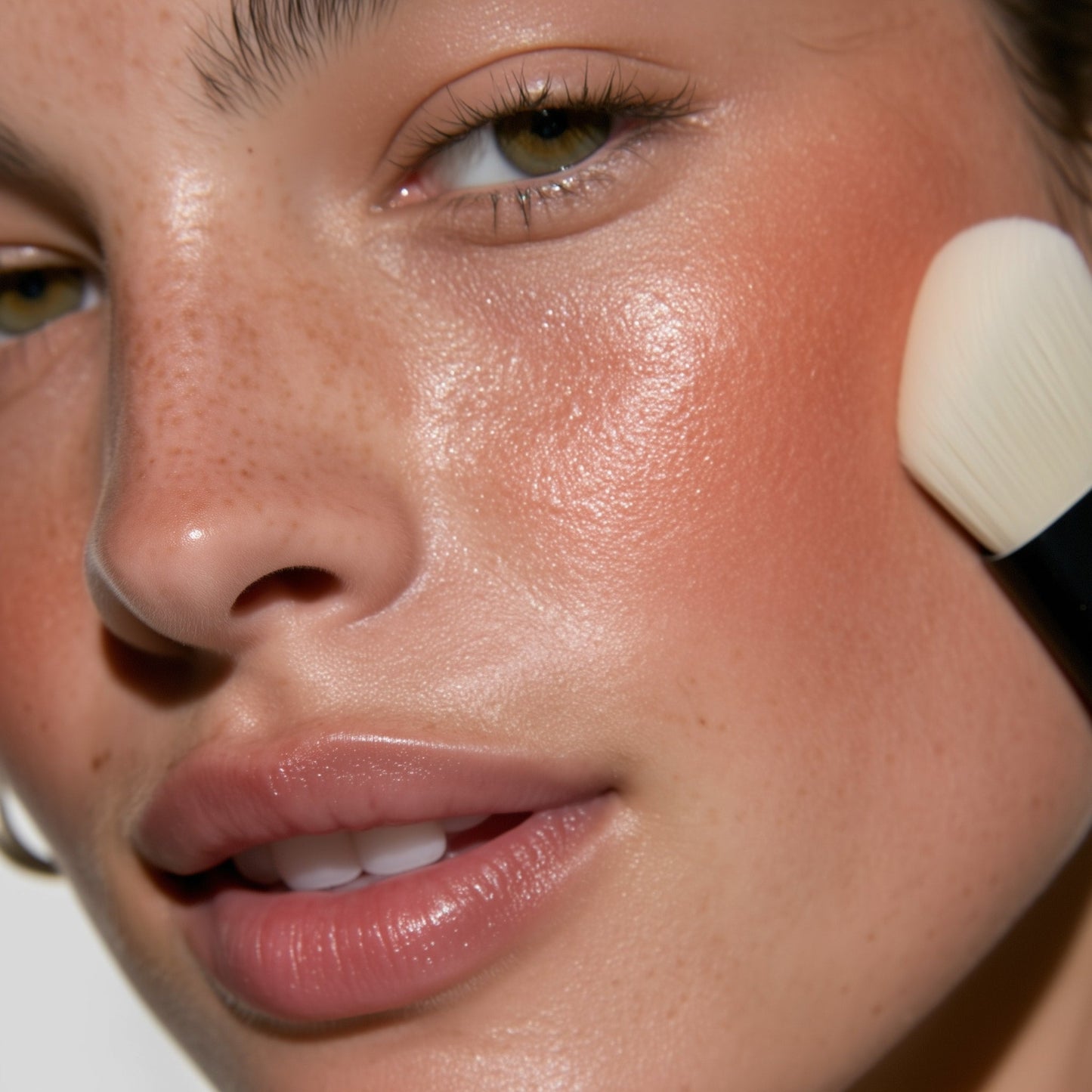 Close-up of a person applying makeup with a brush to their face.