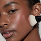 Close-up of a person applying makeup with a brush to their face.