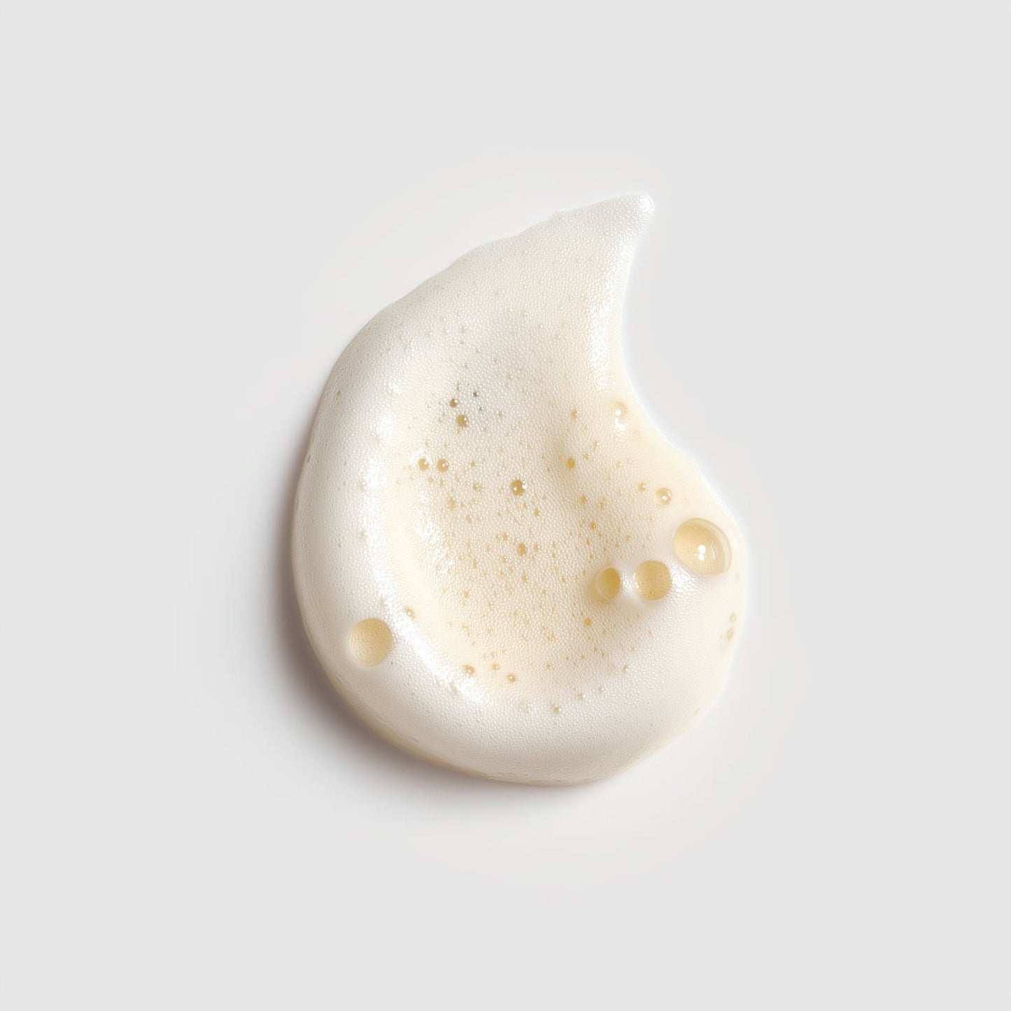 White cream droplet on a light gray background