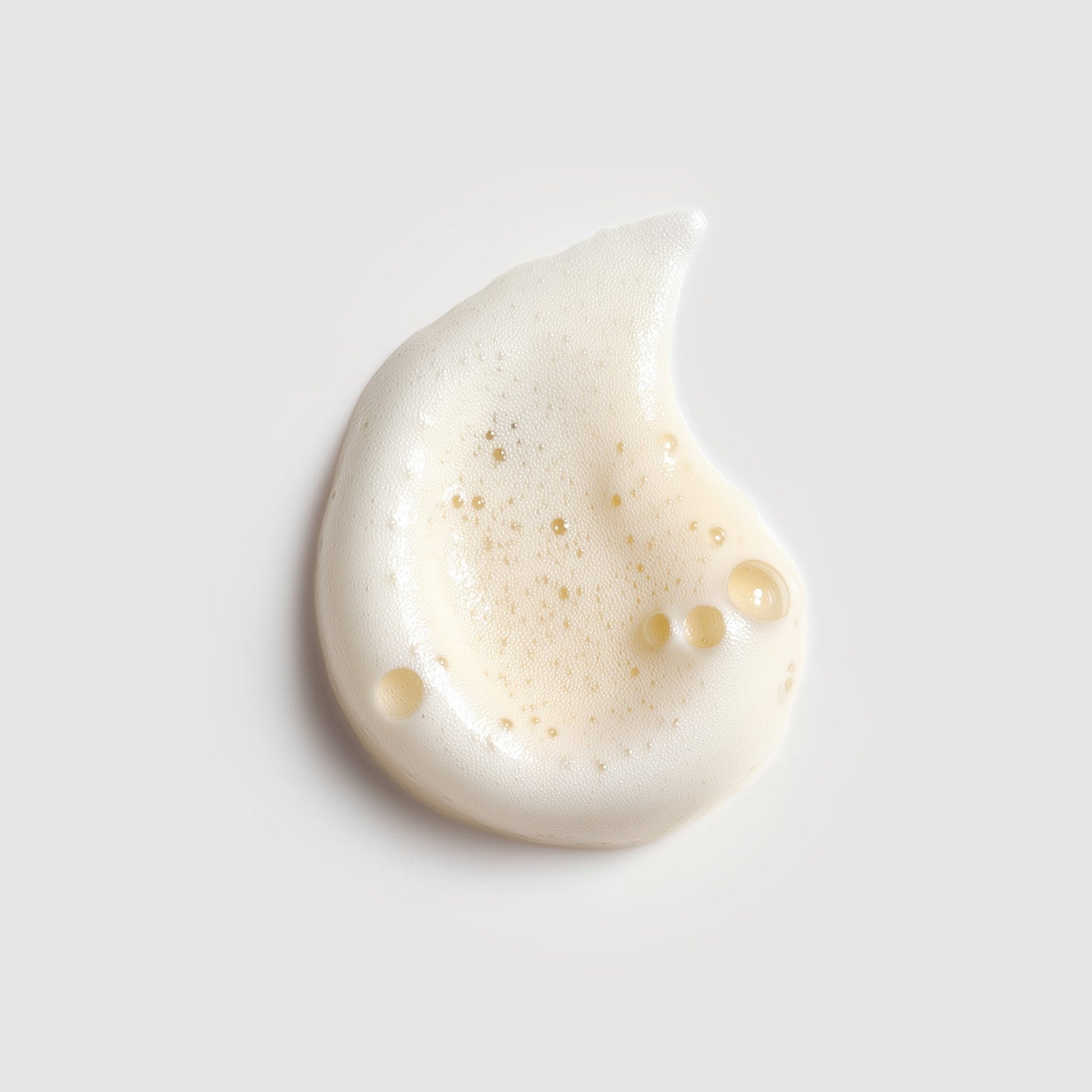 White cream droplet on a light gray background