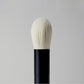 Makeup brush with black handle and white bristles on a gray background