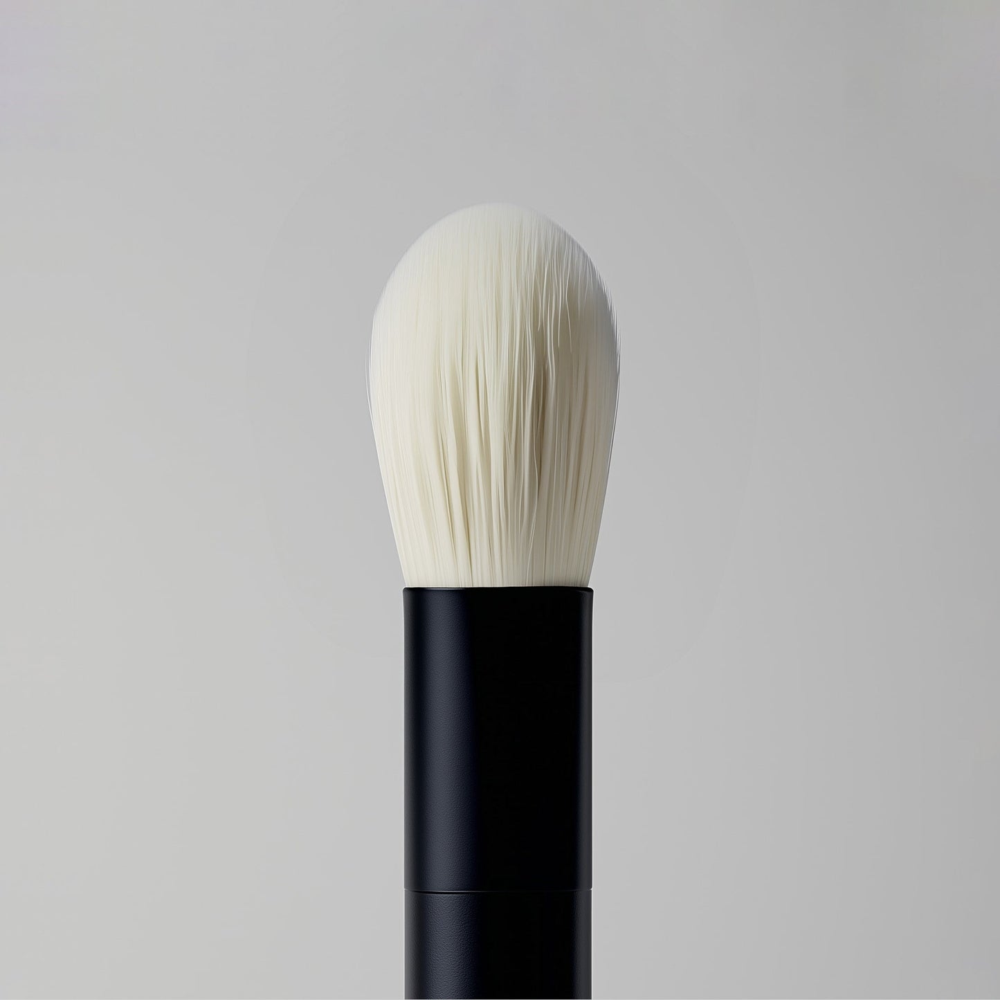 Makeup brush with black handle and white bristles on a gray background