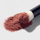 Makeup brush with pink blush powder on a light gray background