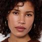 Close-up of a woman with curly hair wearing gold hoop earrings 