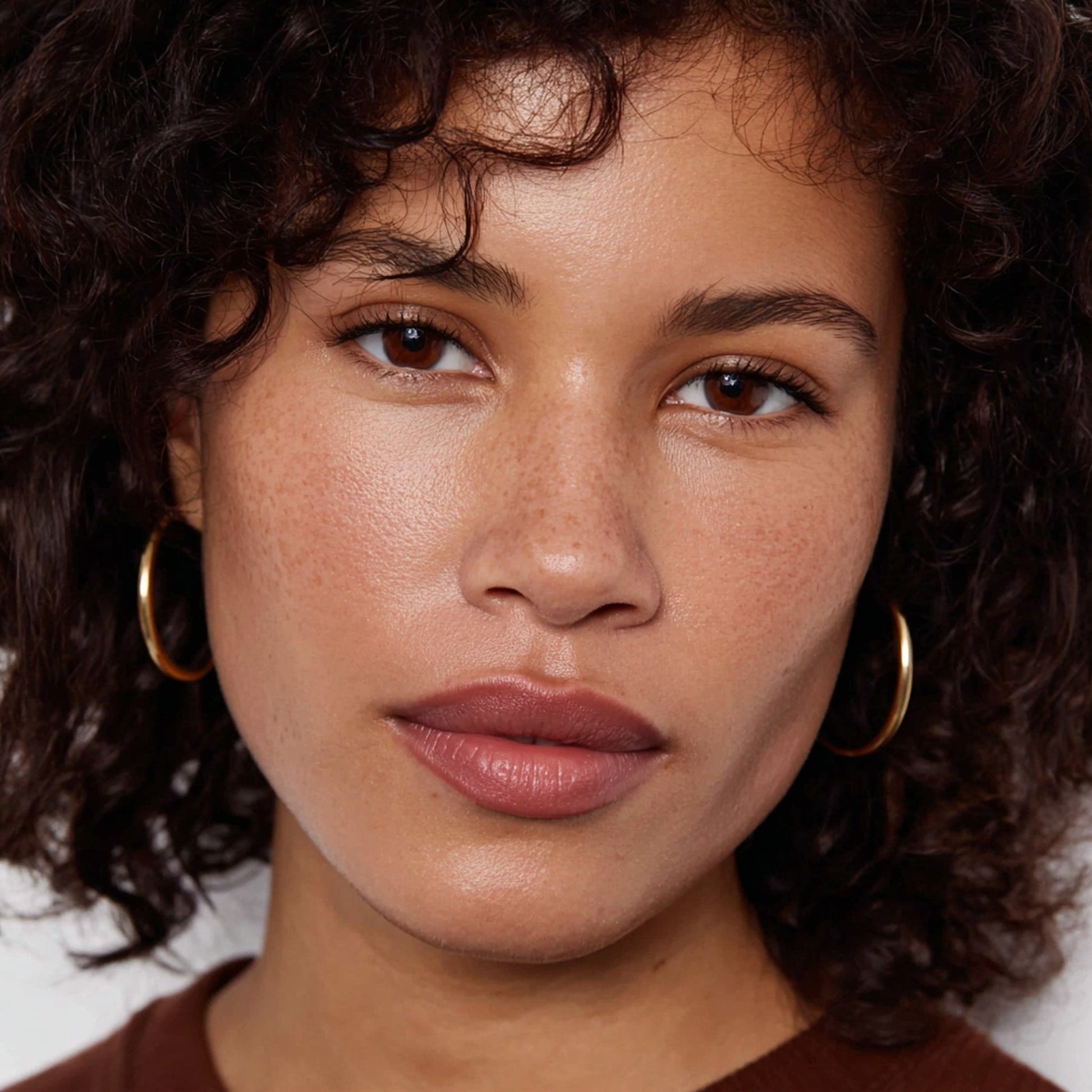 Close-up of a woman with curly hair wearing gold hoop earrings 