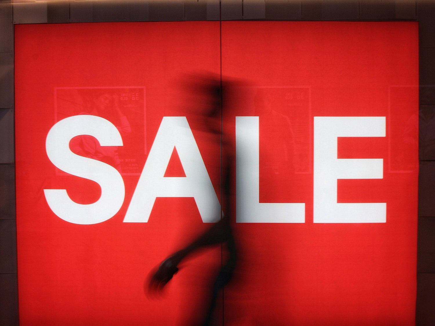 Red sign with 'SALE' in white letters, blurred figure in front