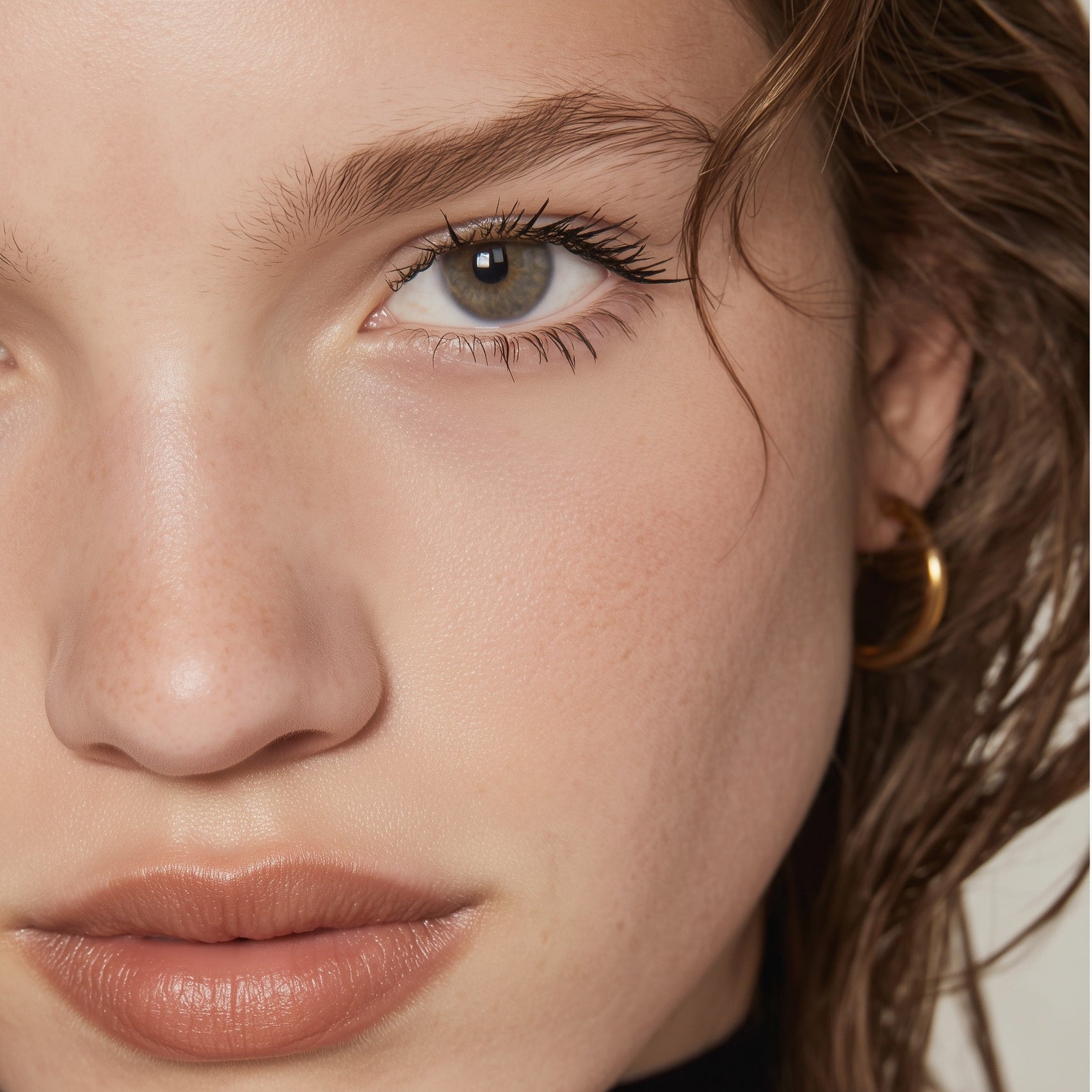 Close-up of a person's face with a gold hoop earring.