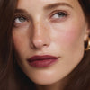 Close-up portrait of a person with freckles and soft, natural makeup.