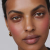 Close-up portrait of a person wearing soft, natural makeup with warm-toned blush.