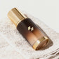 Amber-toned skincare bottle with a metallic gold cap placed on a neatly folded white towel.