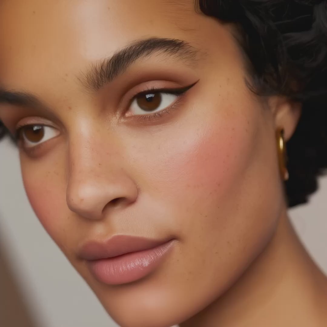 Close-up of a face featuring subtle peach-toned makeup and defined winged eyeliner.