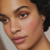 Close-up of a face featuring subtle peach-toned makeup and defined winged eyeliner.