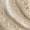 Close-up of a creamy skincare texture with visible droplets and fine exfoliating particles.