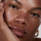 Close-up of a person's face with a hand on their cheek, wearing a gold earring (Dark brown)